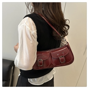 Detail of dark red glossy shoulder bag featuring retro buckle pockets and metal chain strap