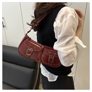 Close-up of wine red glossy underarm bag with double front pockets and silver buckles