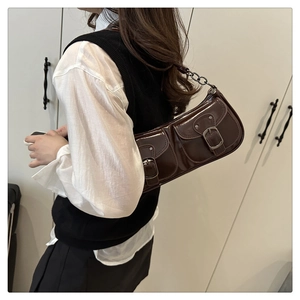 Détail du sac baguette marron foncé brillant avec boucles en métal et bandoulière chaîne