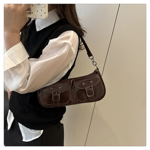 Détail du sac baguette en cuir verni marron foncé avec chaîne et poches utilitaires