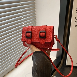 Mini borsa a tracolla rossa con trama litchi e fibbie nere decorative tenuta in mano