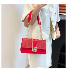 Detail of red crossbody bag featuring glitter flap and elegant gold metal lock buckle