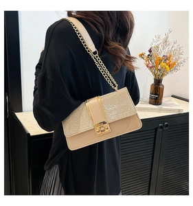 Detail of glittery patchwork beige gold crossbody bag with chain strap on a model