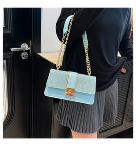 Detail of light blue crossbody bag featuring shimmering fabric and gold metal clasp
