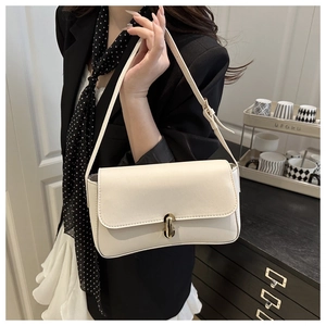 Detail of adjustable strap and gold buckle on a beige leather baguette shoulder bag