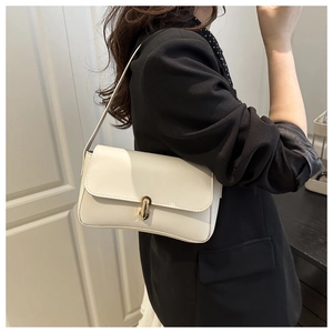 Close-up of stylish cream leather shoulder bag with gold metal buckle on female model
