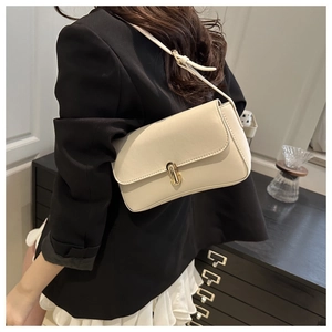 Detail showing elegant gold metal clasp on a smooth cream rectangular baguette bag