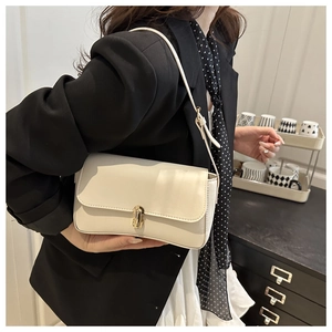 Detail of elegant cream faux leather handbag featuring a refined gold twist-lock closure