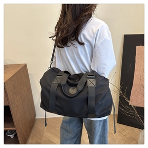 Mannequin portant un grand sac de voyage noir avec bandoulière réglable dans un salon