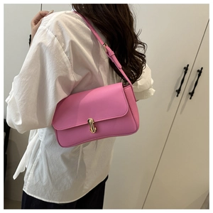 Detail of pink rectangular shoulder bag with golden twist lock worn by a model