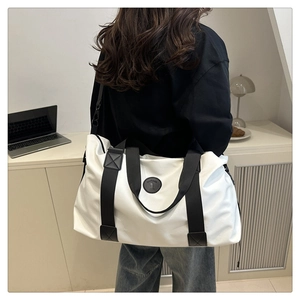 Close-up of white waterproof travel bag featuring reinforced black straps and fashion patch