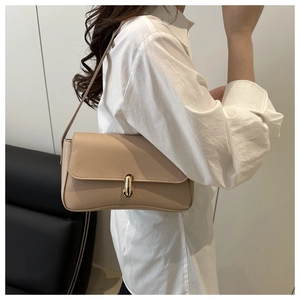 Detail of minimalist beige underarm bag featuring a metallic gold twist-lock buckle