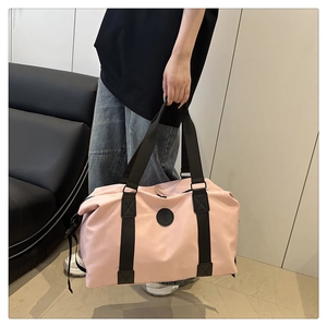 Close-up of light pink travel bag with black handles and matte waterproof fabric
