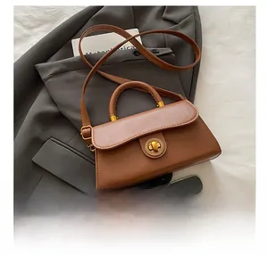 Detail view of a vintage brown handbag with metal twist lock on a grey blazer