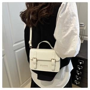 On-body shot of a white retro small square bag with golden buckles and top handle