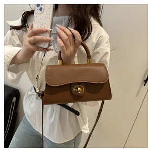 Close-up of caramel leather bag featuring a gold metal twist lock and smooth texture