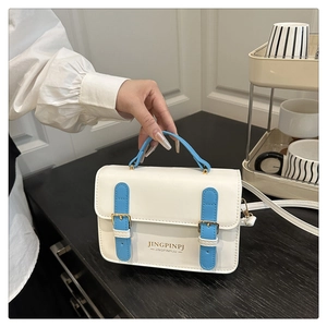 Dettaglio ravvicinato della borsa in pelle crema con cinturini blu e fibbia in metallo oro