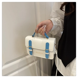 Dettaglio mini borsa a tracolla bianco crema con manico azzurro e fibbia dorata