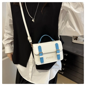 Detailed view of the white and blue crossbody bag with gold buckles and adjustable strap