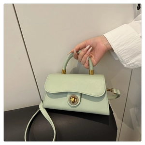 Close-up of mint green leather crossbody bag with circular gold twist lock hardware