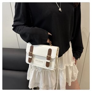 Detail of white and brown faux leather crossbody bag with gold-tone magnetic buckle straps