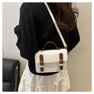 Detailed view of a white vintage crossbody bag with brown leather accents and gold clasp