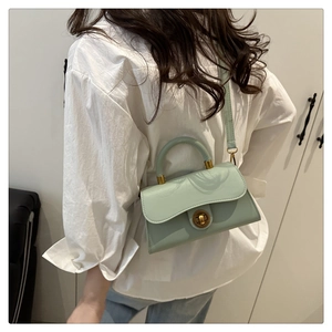 Detail of mint green PU leather crossbody bag with golden twist lock and top handle