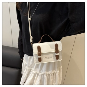 Close-up of a white vintage crossbody bag with brown handles and gold buckle detail