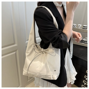 Detail einer schicken cremefarbenen Hobo-Tasche mit Schleife, getragen zum Blazer