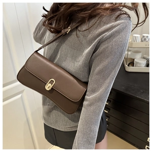 Model wearing a deep brown vintage baguette bag with gold buckle in a modern setting