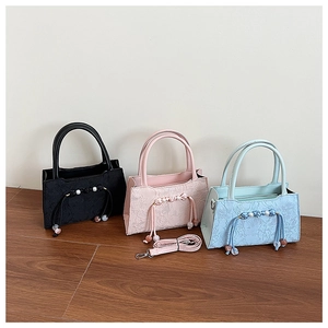 Detailed view of floral lace handbags in black, pink, and blue with pearl pendants