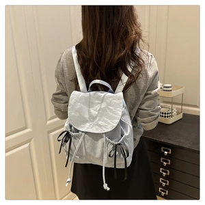Détail du sac à dos en nylon bleu clair avec nœuds en satin noir et broderie de marque
