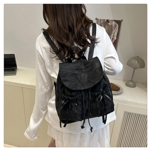 Vue détaillée du sac à dos noir texturé avec nœuds en ruban et fermeture à cordon