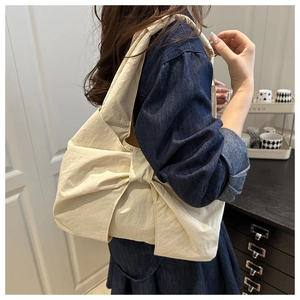 Detail of cream denim tote bag featuring a large bow and comfortable wide strap