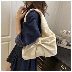 Détail d'un sac à bandoulière blanc crème avec nœud en nylon plissé sur modèle