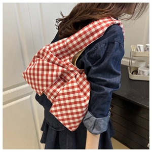 Détail du sac à bandoulière en toile à carreaux rouge et blanc avec un grand nœud stylé