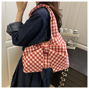 Détail du sac à bandoulière à carreaux rouges et blancs avec un grand nœud en tissu doux