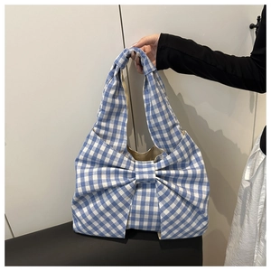 Détail du sac à main à carreaux bleus et blancs avec un grand nœud décoratif et tissu doux