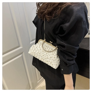 Detail of off-white pearl clutch bag with floral embroidery and gold chain strap