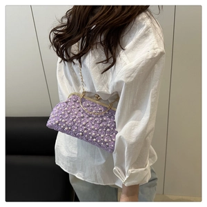 Detailed view of purple floral crossbody bag with pearl embellishments and gold clasp