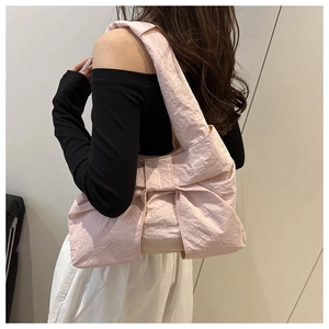 Détail du sac bandoulière rose avec grand nœud et texture plissée en tissu doux