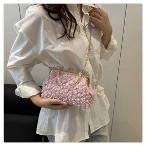 Detail of pink floral handbag featuring 3D fabric flowers, pearls, and a gold chain strap
