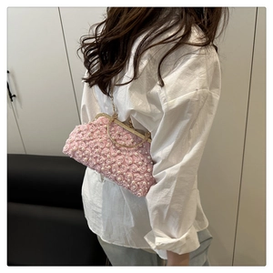 Sac de soirée rose avec fleurs et perles porté par un mannequin à l'épaule