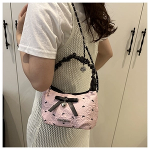 Detail of pink seersucker underarm bag with black bows and a silver heart pendant