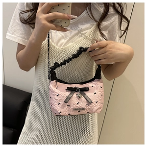 Detail of pink pleated bag with black satin bow, heart charm and fashion metal logo