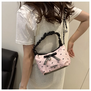 Sac hobo plissé rose avec nœud noir et breloque en forme de cœur vue de côté