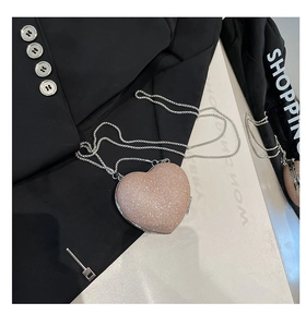 Dettaglio di mini borsa a cuore con paillettes rosa e tracolla a catena d'argento