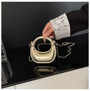 Detalle de bolso de fiesta de metal dorado con asa redonda y elegante forma de luna