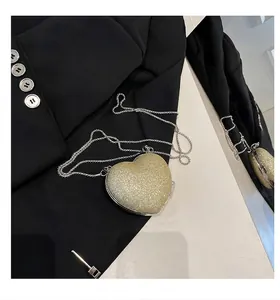 Elegante borsa da sera dorata a cuore con tracolla a catena su blazer nero