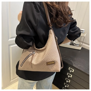 Detalle del bolso tote marrón de espiga con bolsillo de cremallera y etiqueta de moda